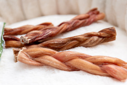 Braided dog  bully sticks on a white surface with a blurred background