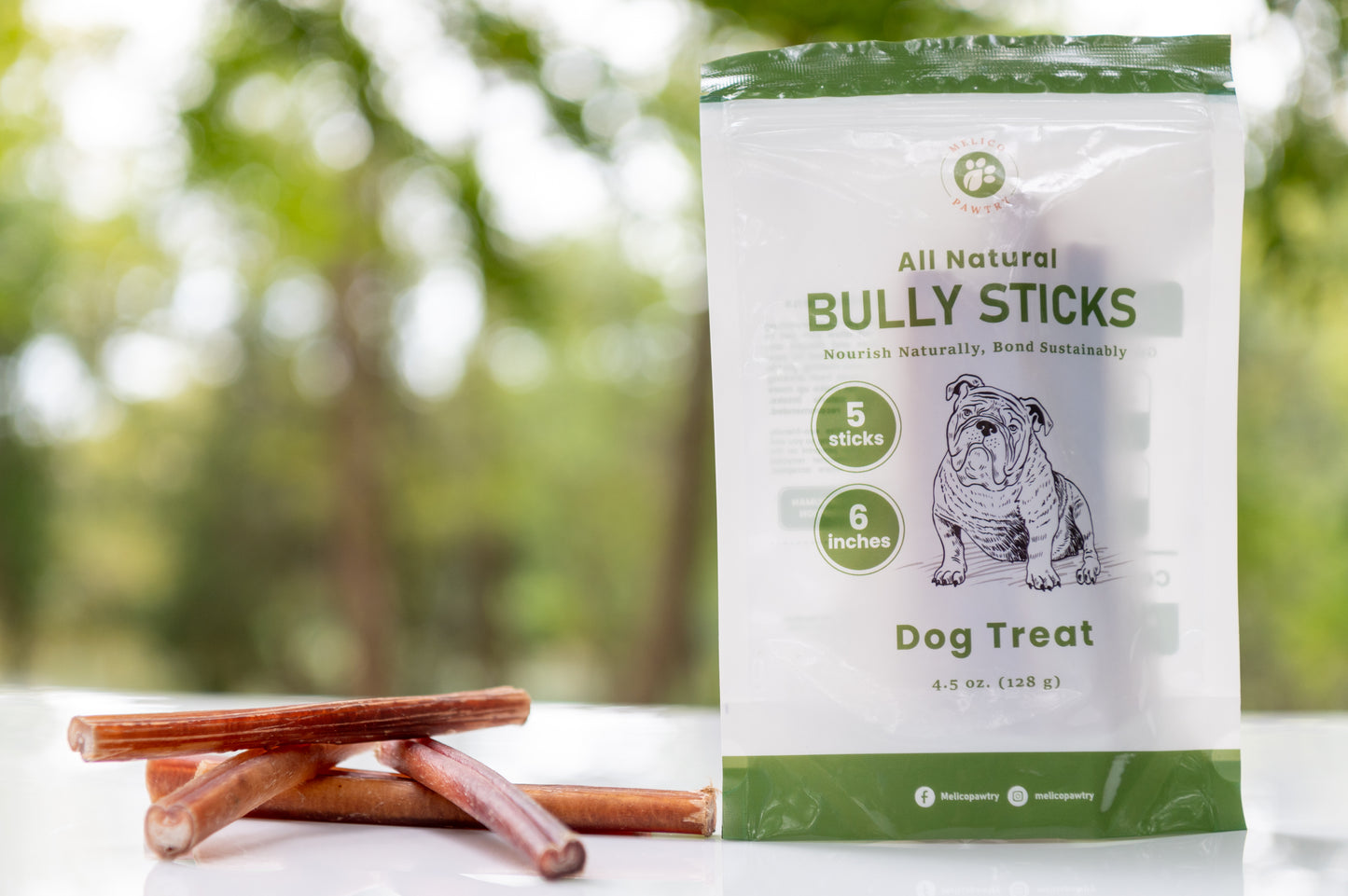 Bag of all natural bully sticks dog treats with two sticks on a blurred natural background