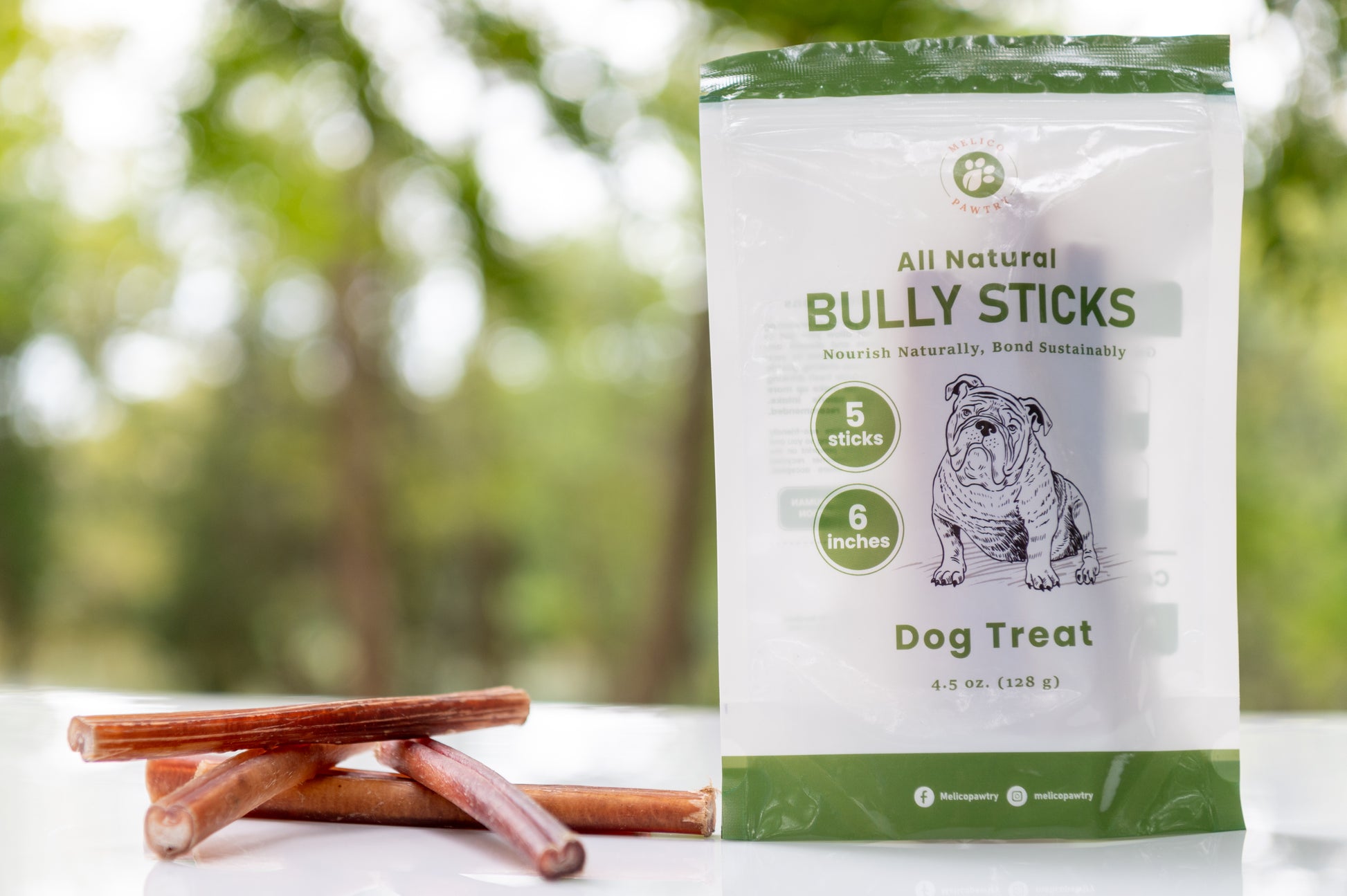 Bag of all natural bully sticks dog treats with two sticks on a blurred natural background
